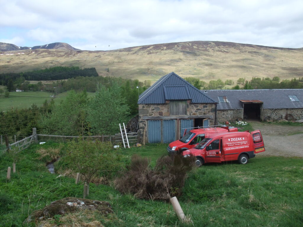 Two vans in a rural setting by a barn