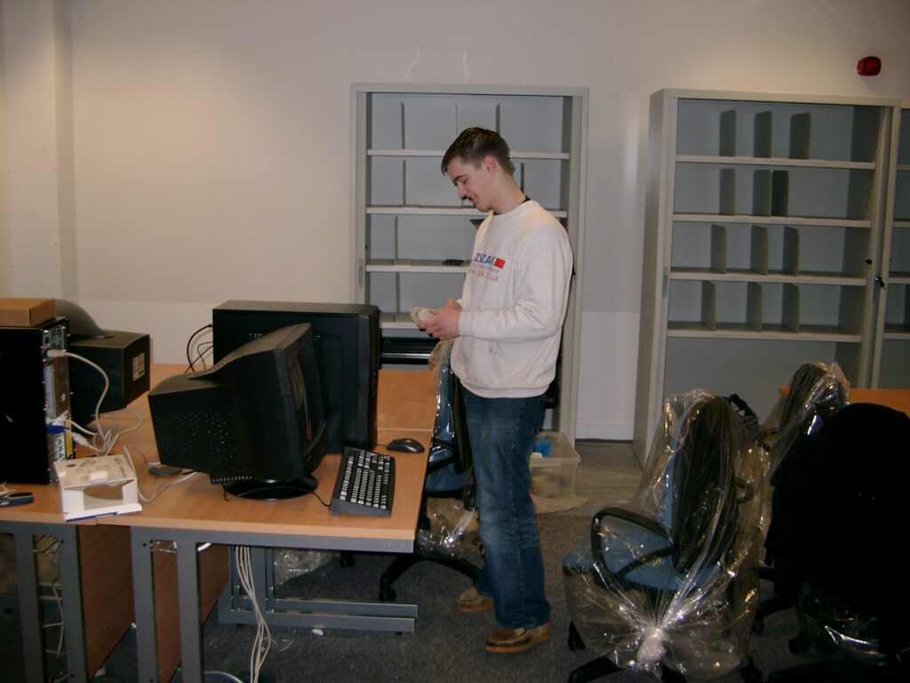 A man setting up a new computer on a classroom desk