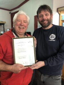 Two men standing hold a framed certificate
